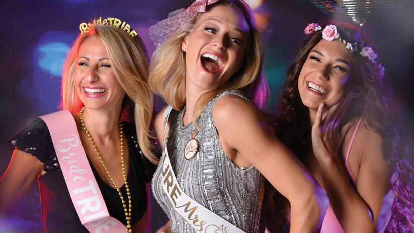 Bachelorette party celebration with bride-to-be and friends wearing sashes and festive accessories, perfect for a fun night out or bridal party theme.