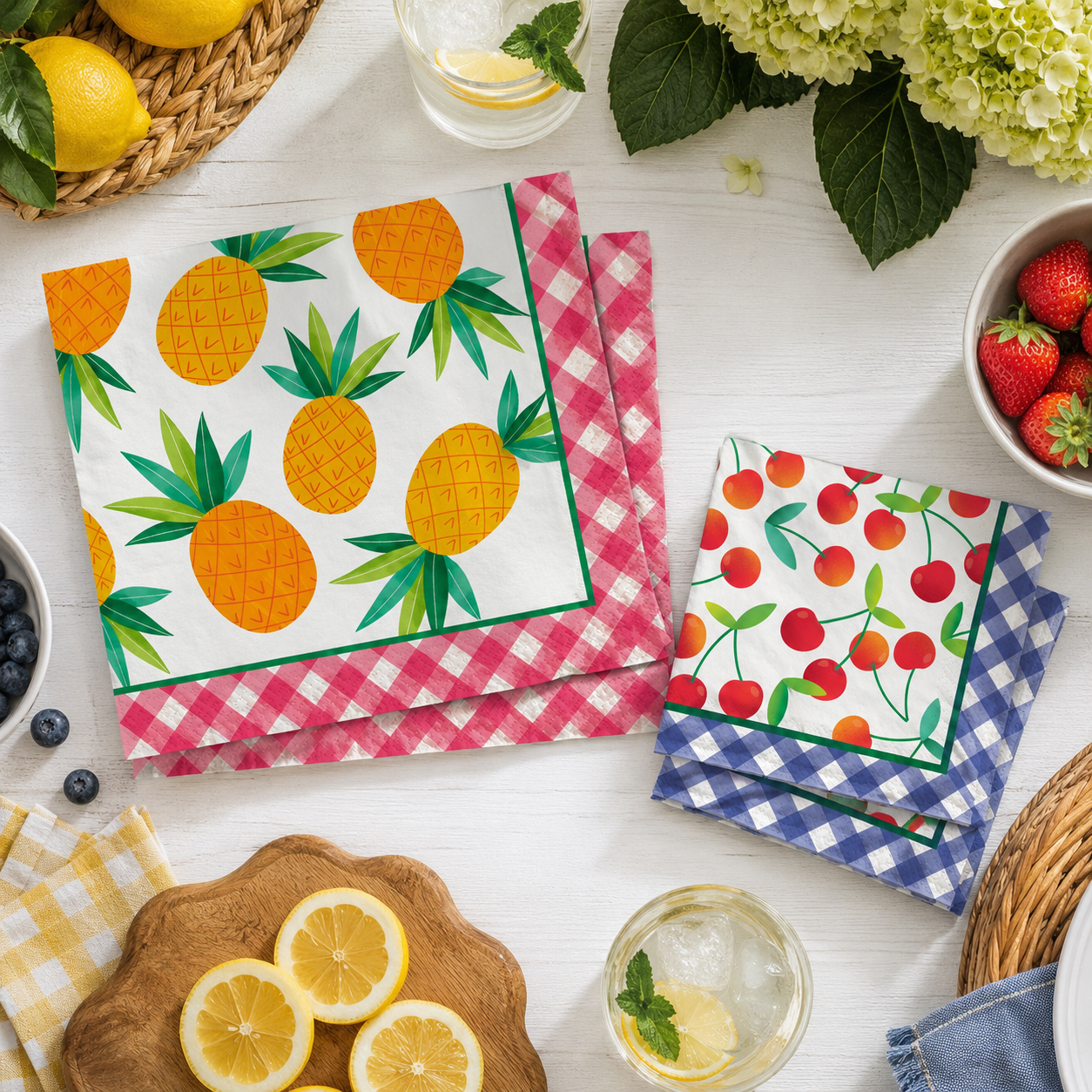 Colorful paper napkins with pineapple and cherry designs on a white table with lemons and strawberries.