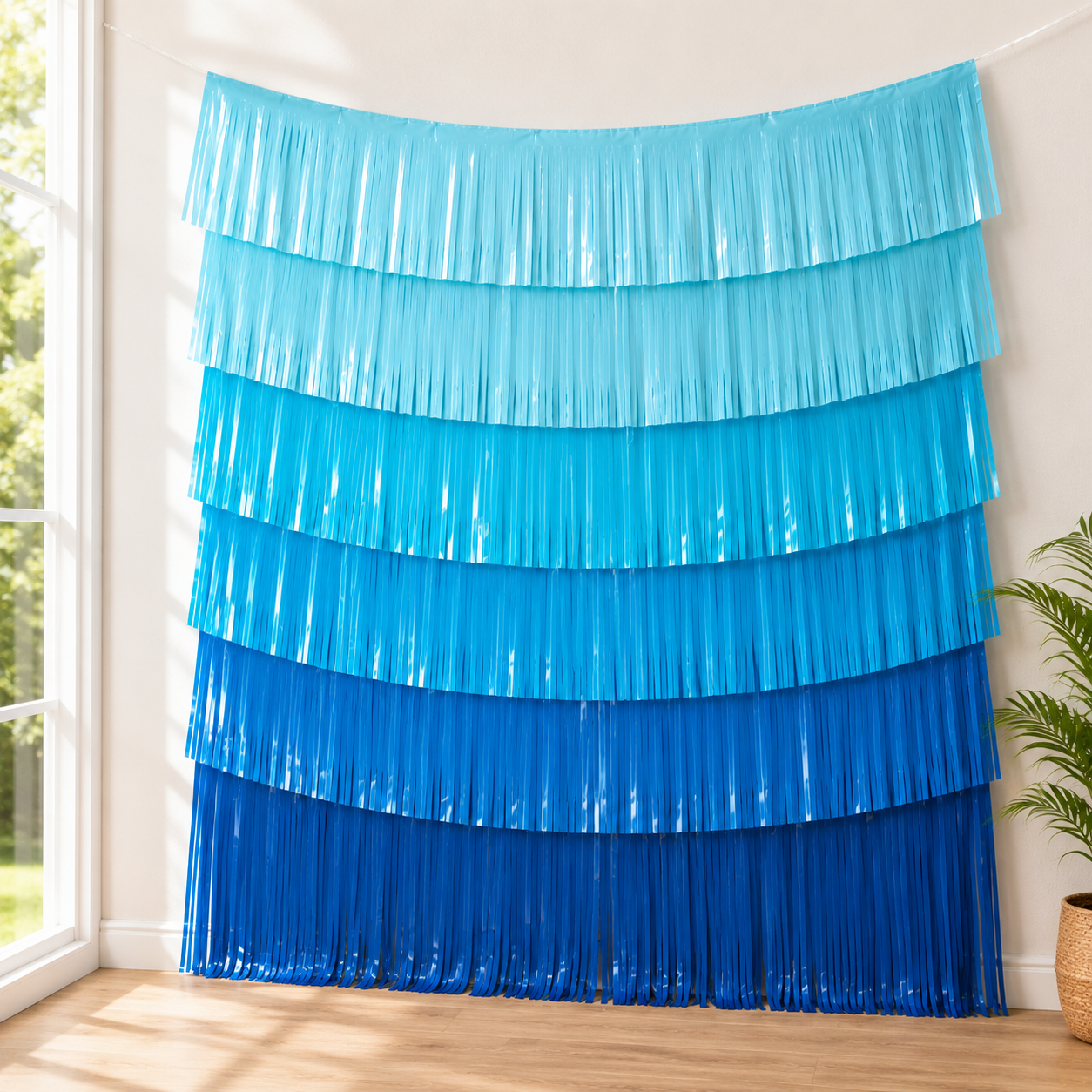 Blue fringe curtain hanging in a room with a window and plant.